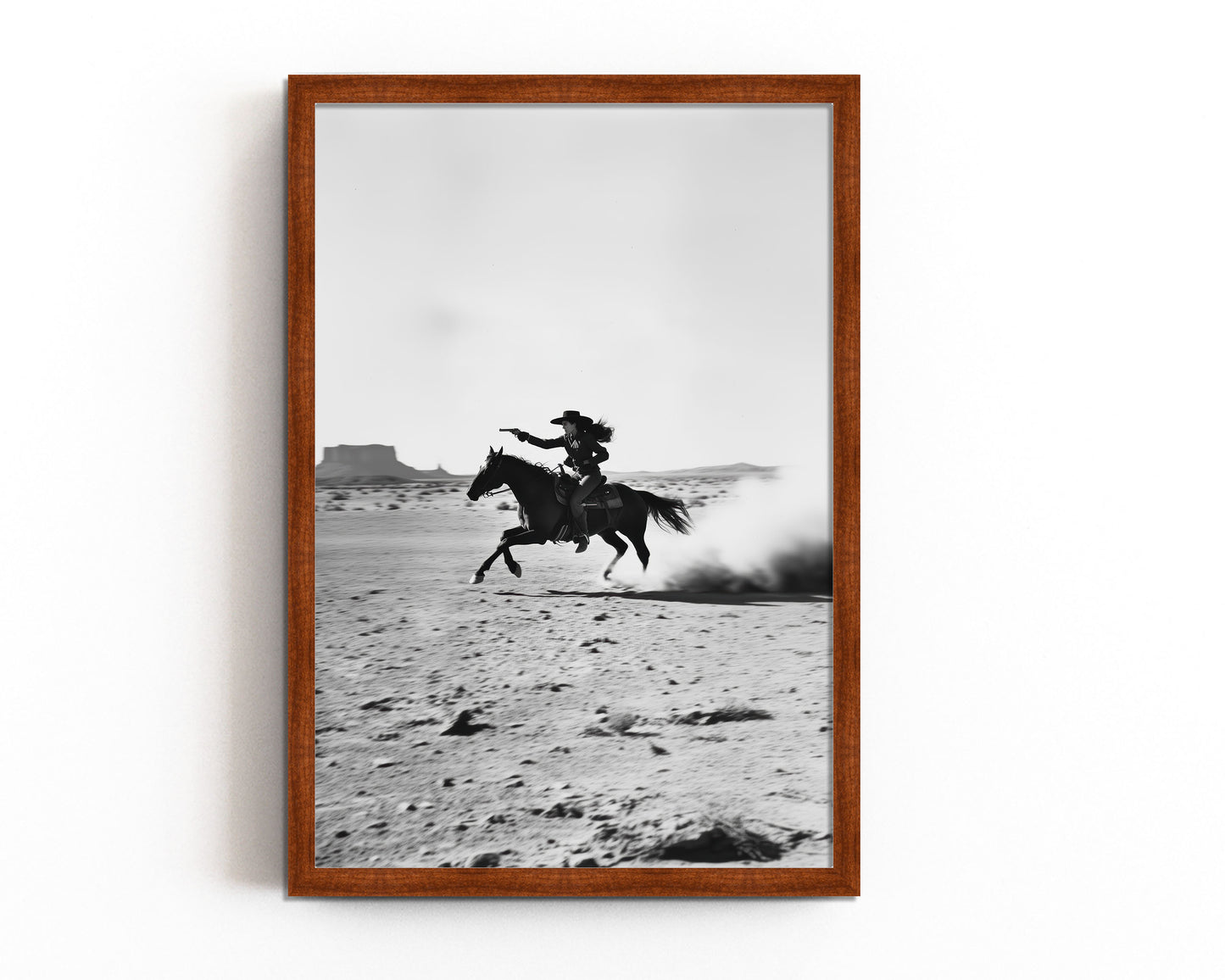 A black-and-white photograph of a cowboy galloping on horseback through the desert, with dramatic light and shadow across the sand.