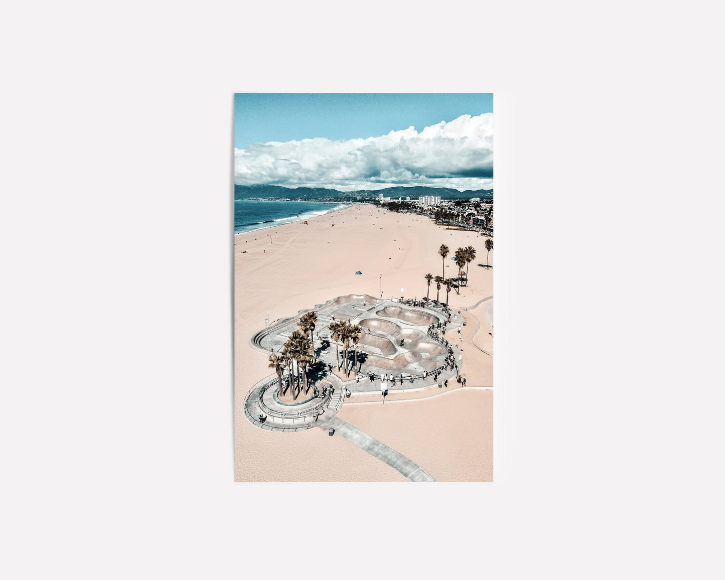 Aerial beach photography of Venice Beach skatepark, featuring golden sands, palm trees, and the Pacific Ocean, blending urban and coastal vibes.
