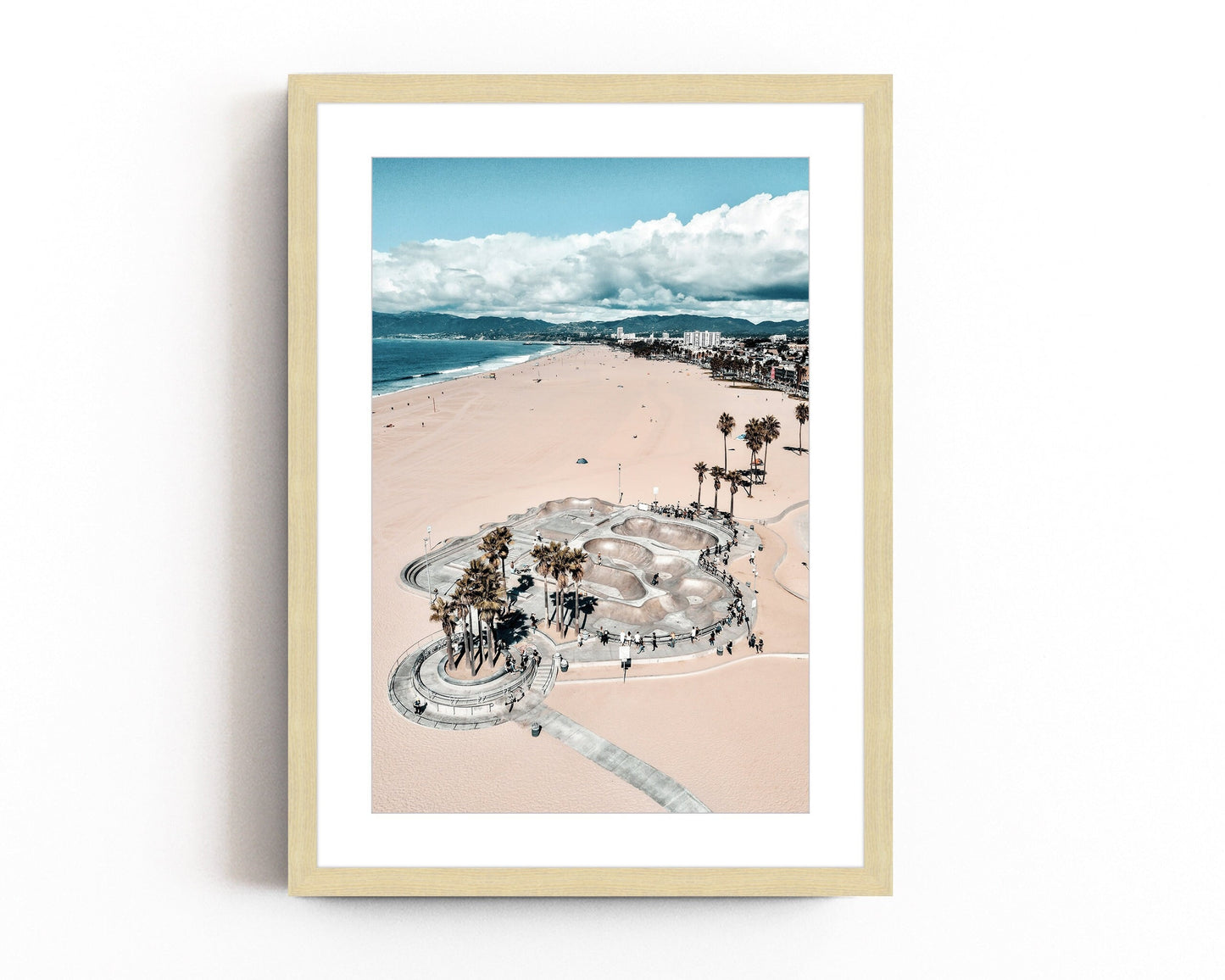 Aerial beach photography of Venice Beach skatepark, featuring golden sands, palm trees, and the Pacific Ocean, blending urban and coastal vibes.