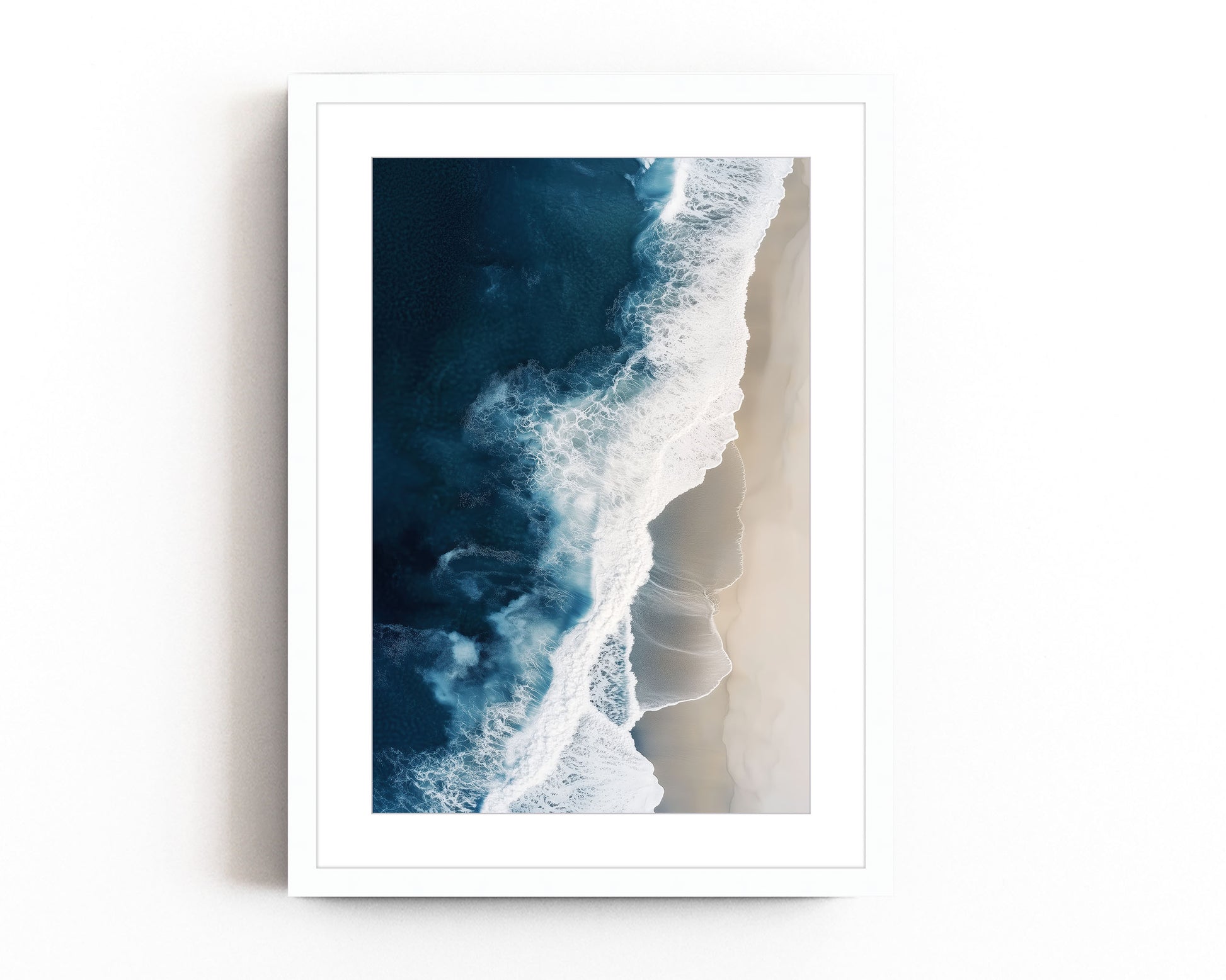 Aerial view of ocean waves crashing onto a sandy beach, showcasing deep blue waters and minimalist coastal scenery, perfect for modern beach home decor.