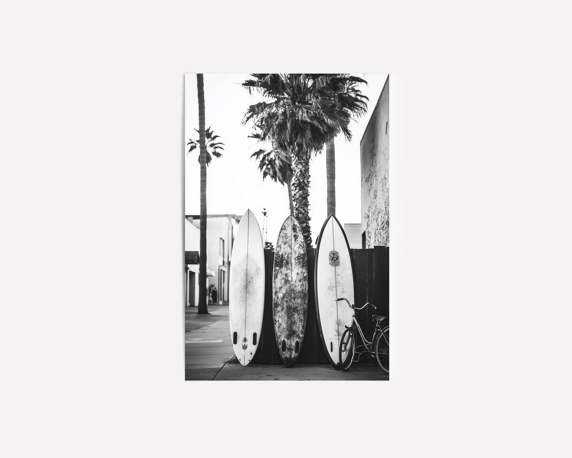 Black and white photograph of surfboards resting against palm trees on a tropical beach, perfect for vintage surf-inspired decor and coastal homes.