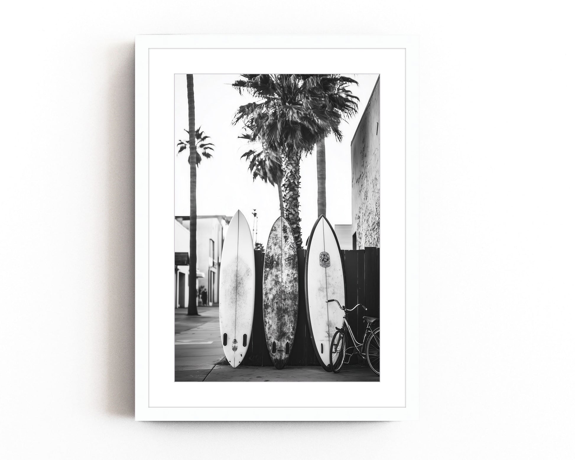 Black and white photograph of surfboards resting against palm trees on a tropical beach, perfect for vintage surf-inspired decor and coastal homes.