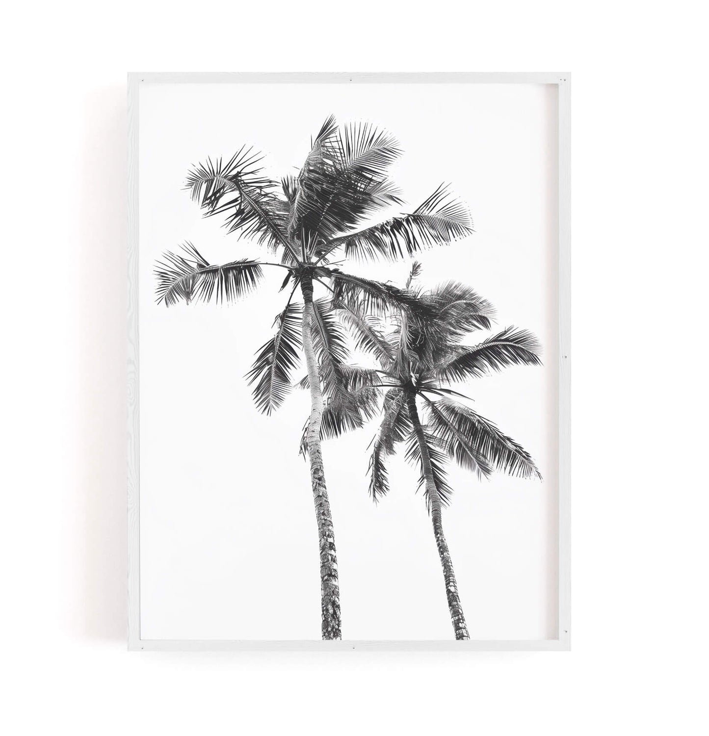 A framed black and white art print depicting two palm trees against a white background, presented in a light-colored frame.