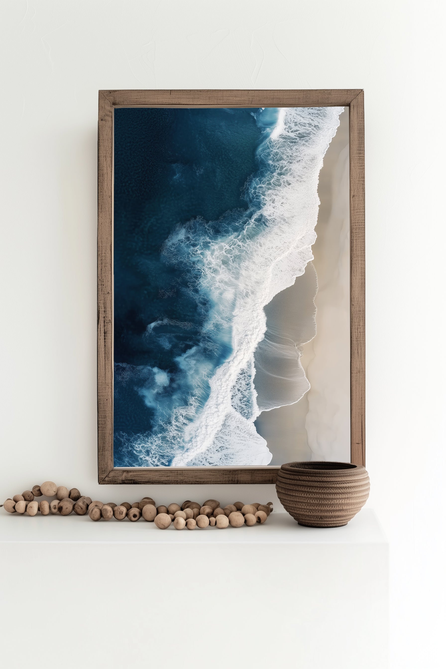 Aerial view of ocean waves crashing onto a sandy beach, showcasing deep blue waters and minimalist coastal scenery, perfect for modern beach home decor.