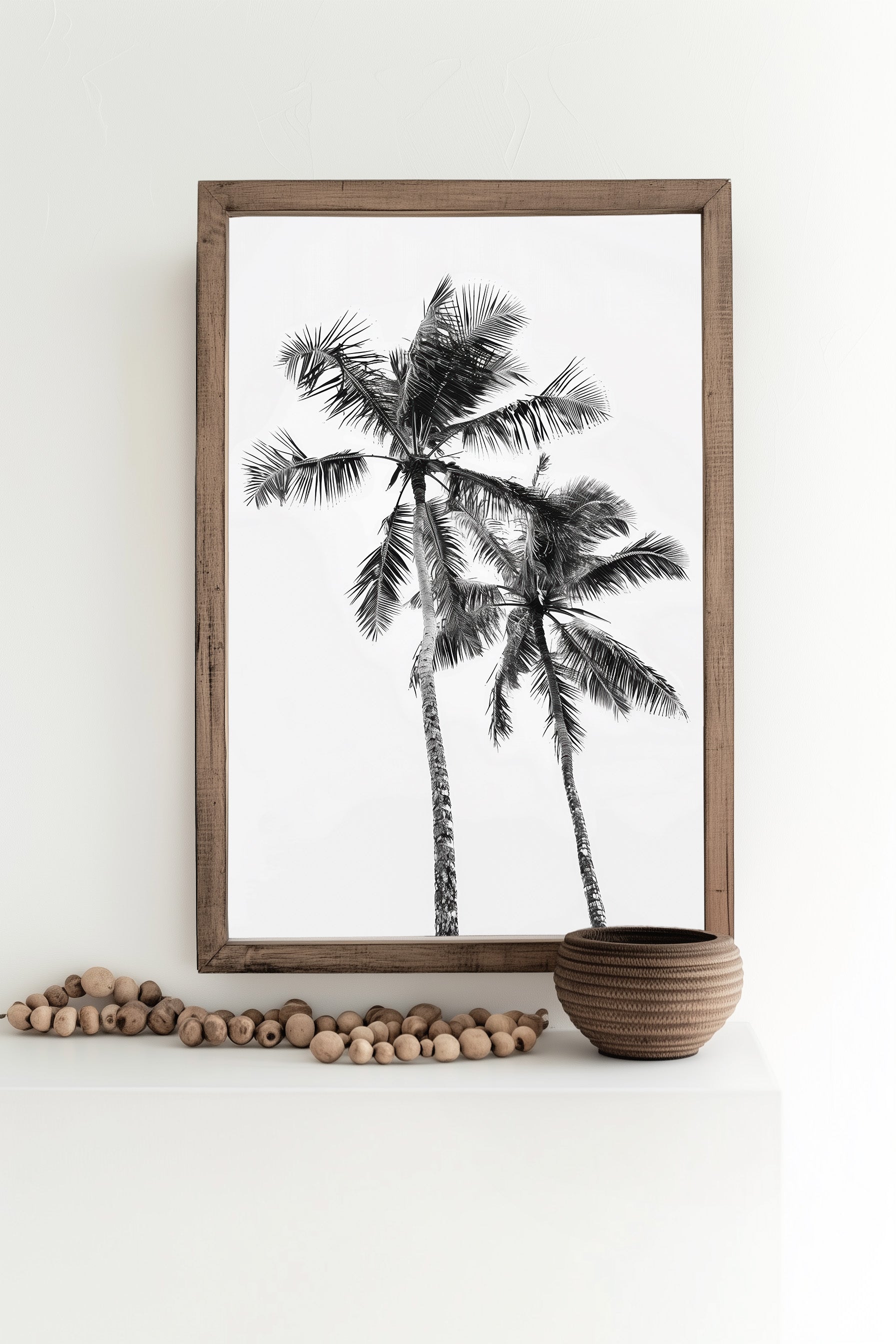  Monochrome black and white photograph of two palm trees set against a minimal sky, ideal for tropical-inspired modern home decor and nature wall art, shown  in a beach house as wall art decor

