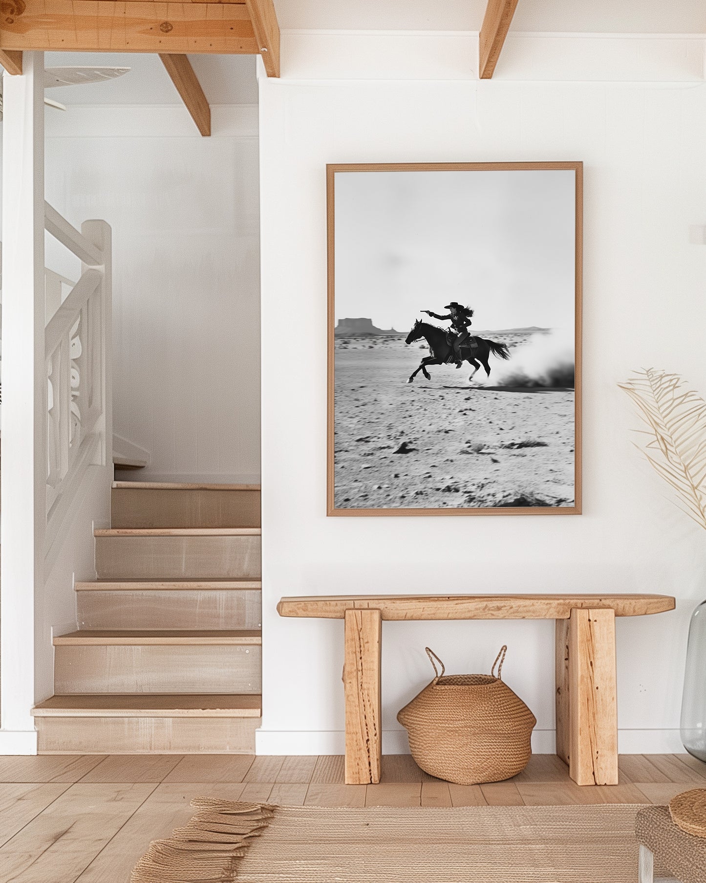 A black-and-white photograph of a cowboy galloping on horseback through the desert, with dramatic light and shadow across the sand.