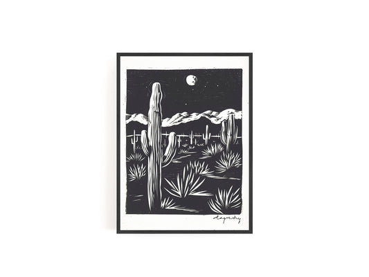 Black and white print featuring a cactus and desert landscape under a full moon, showcasing a minimalist Southwestern scene.