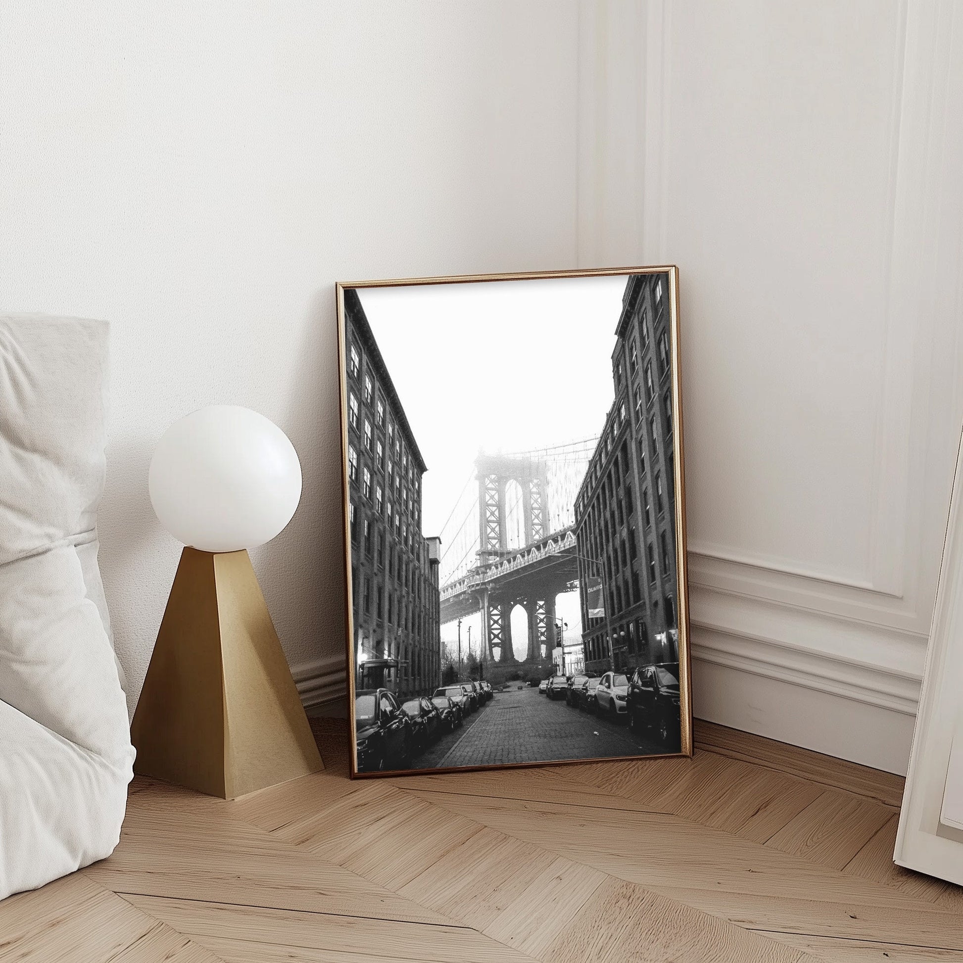  Black and white photography of the Manhattan Bridge framed between two buildings in DUMBO, Brooklyn, capturing the timeless beauty of NYC architecture.