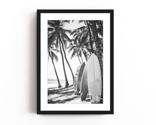 Black and white surfboard art print featuring surfboards resting on a beach under palm trees, capturing the essence of coastal living.
