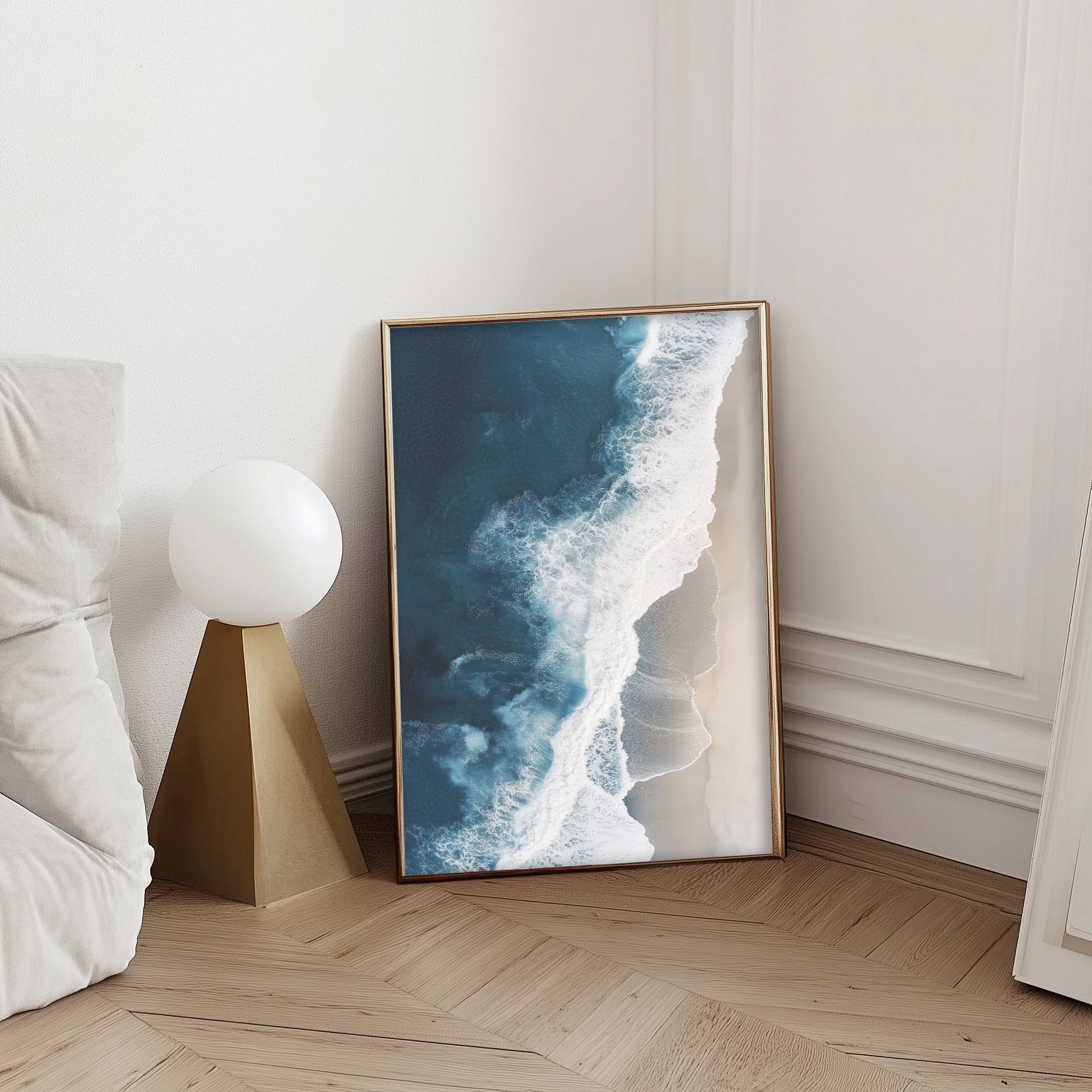 Aerial view of ocean waves crashing onto a sandy beach, showcasing deep blue waters and minimalist coastal scenery, perfect for modern beach home decor.