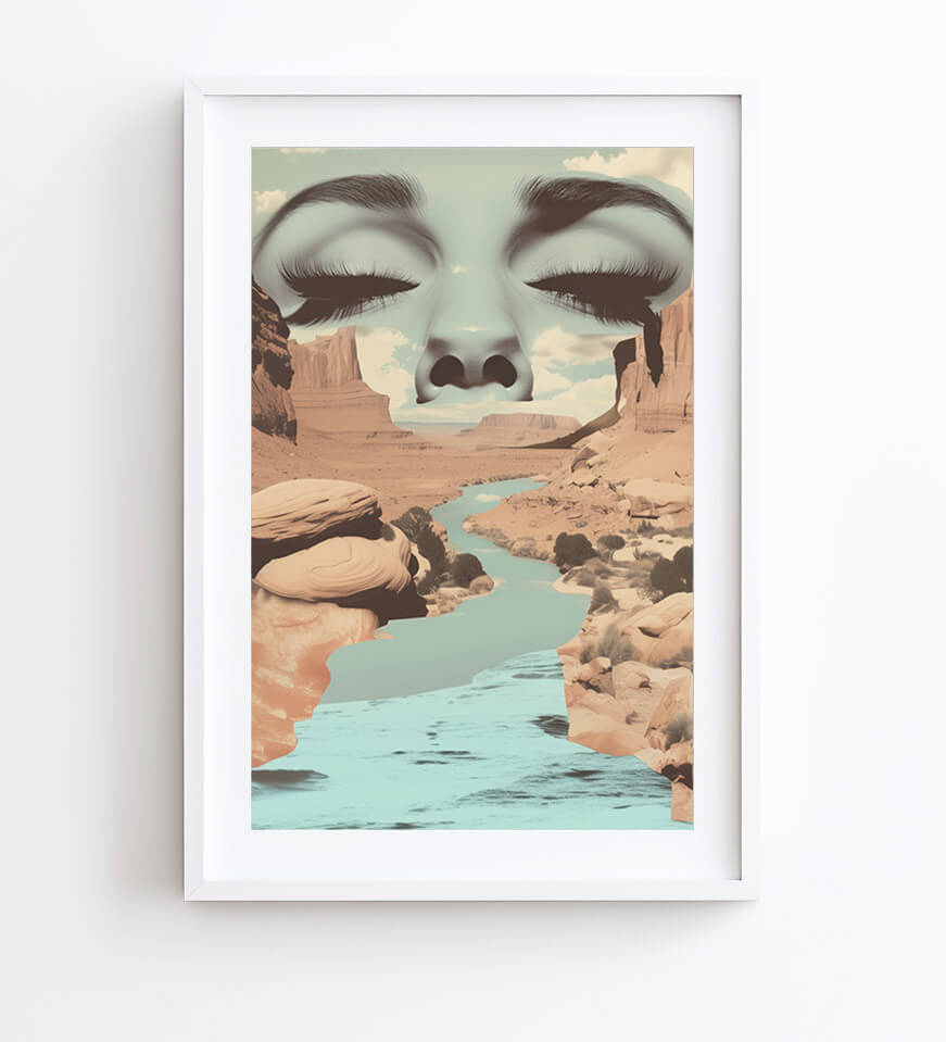 A framed art print featuring a surreal desert canyon landscape with a turquoise river and a large stylized face emerging from the rocks, shown in a white frame against a light gray wall.