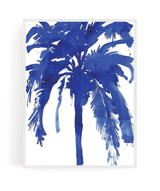 A framed wall art print featuring a stylized blue watercolor palm tree on a white background, shown against a light gray wall.